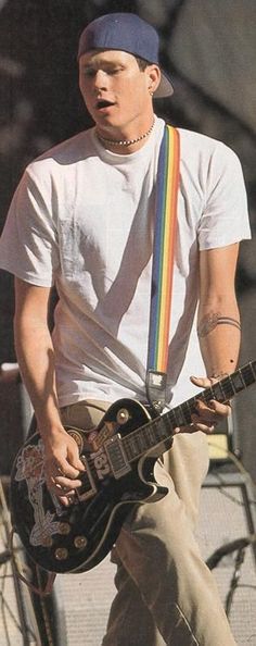 a man with a hat playing an electric guitar on stage at a music festival or concert