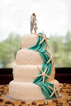 a wedding cake with starfish decorations and a bride and groom figurine on top