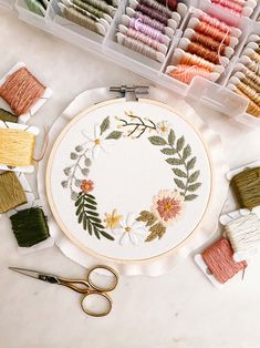 the embroidery kit is on the table with scissors and thread spools next to it