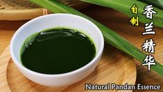 a bowl filled with green liquid sitting on top of a wooden tray next to bamboo sticks