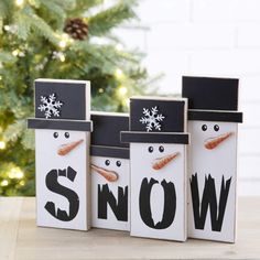 three snowmen are standing in front of a christmas tree