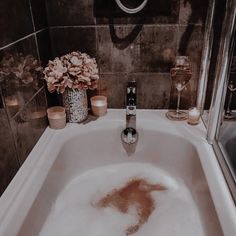 a bathtub filled with foam next to candles and flowers