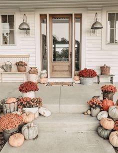 pumpkins and gourds are sitting on the front porch