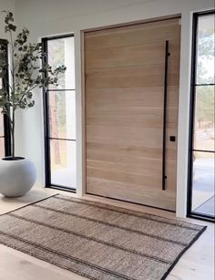 a white vase sitting on top of a rug in front of a wooden entry door