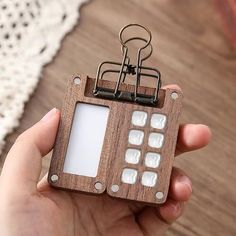 a person holding a wooden keychain with a cell phone attached to the front