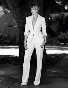 a woman in a white suit standing next to a tree