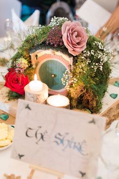 a table topped with candles and flowers next to a small hobbot shaped sign