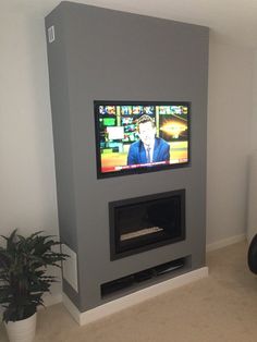 a flat screen tv mounted to the side of a wall in a living room next to a potted plant