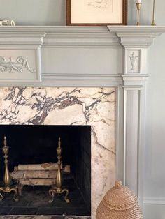 a fireplace with white marble and gold accents