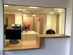 an office cubicle with a desk and computer monitor in the reflection on the wall