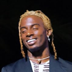 a close up of a person wearing a suit and tie with dreadlocks on