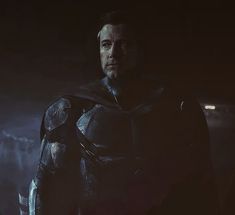 a man dressed as superman standing in the dark