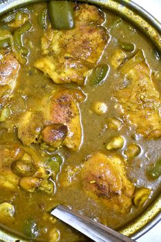 a pan filled with meat and vegetables covered in gravy next to a spoon