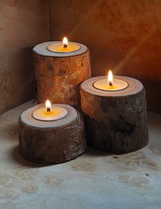 three lit candles sitting on top of logs