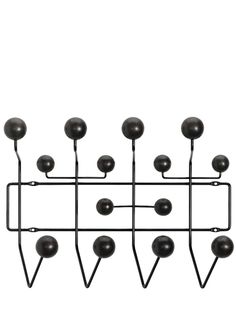 a metal rack with black balls hanging from it's sides on a white wall