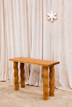 a wooden bench sitting in front of curtains