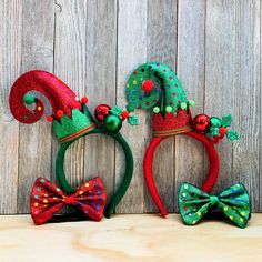 two red and green christmas hats with bows on them, one wearing a santa hat