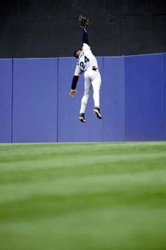 a baseball player jumping in the air to catch a ball