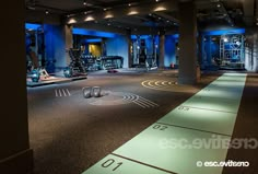 an indoor gym with treadmills and blue lighting