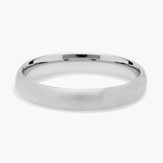 a white gold wedding ring on a plain surface, with a slight edge and rounded edges