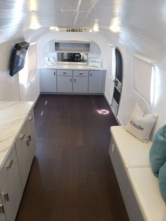 the inside of an airplane with wood flooring and white cabinets on each side of the room