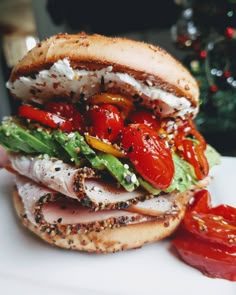 a sandwich with tomatoes, lettuce and other toppings on it next to a christmas tree