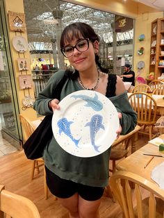 a woman holding a plate with two dolphins on it