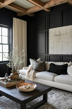 a living room with black walls and white couches, coffee table and rugs