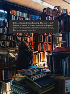 a woman sitting in front of a bookshelf filled with books and looking at it