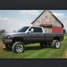 a gray truck parked in front of a barn