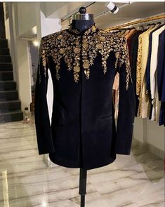 a black jacket with gold embroidered details on it in a store display case next to some clothes