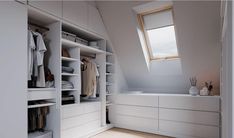 an attic bedroom with white closets and open shelving in the corner, along with a skylight