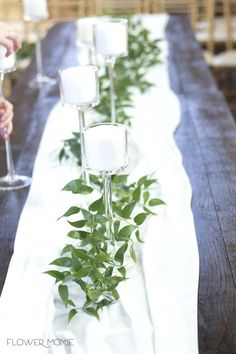 a long table with candles and greenery on it