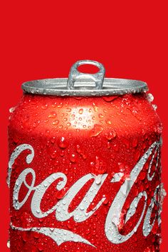 a can of coca - cola with water droplets on the top and bottom, sitting in front of a red background