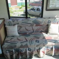 a couch sitting in front of a window next to a stove top oven and microwave