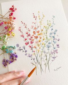 a person is painting flowers with watercolors on paper