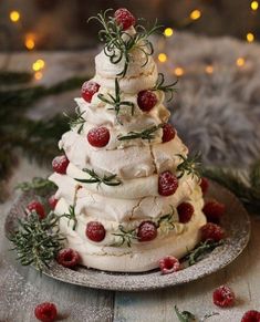 a white cake decorated with strawberries and greenery on a plate next to christmas lights