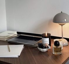 a laptop computer sitting on top of a wooden desk next to a lamp and other items