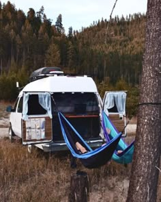 an rv parked in the woods with a hammock hanging from it's roof