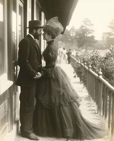 a man and woman standing next to each other in front of a building with flowers