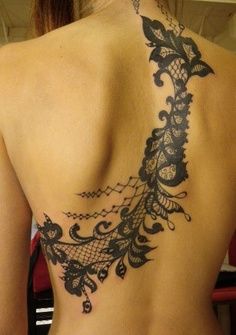 the back of a woman's tattoo with black lace on her upper and lower back