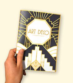 a person holding up a book with art deco on it