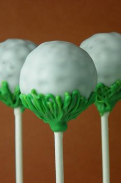 four cake pops with green frosting on them sitting in front of a brown wall