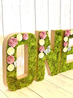 the letters are made out of moss and have flowers on them, as well as butterflies