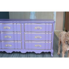 a dog standing next to a purple dresser