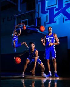 three men in blue uniforms are playing basketball