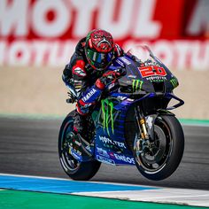 a man riding on the back of a motorcycle down a race track