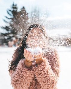 a woman blowing snow in the air with her hands and face covered by white powder