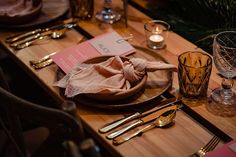 a wooden table with silverware and napkins on it, along with other place settings