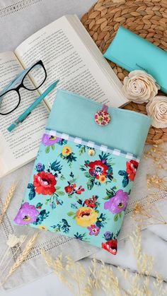 an open book sitting on top of a table next to some glasses and a straw hat